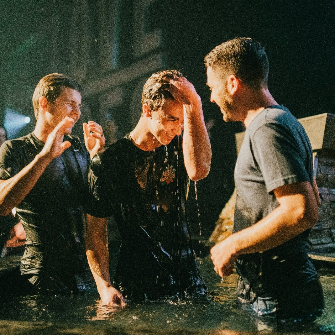 A student being baptized surrounded by church leaders and community